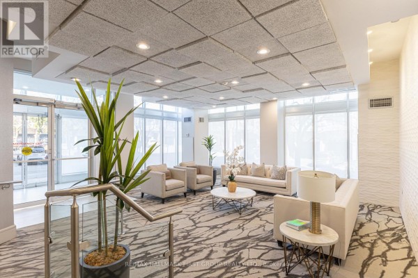 Building lobby furnished with sofas, armchairs, plants, and a patterned carpet. - 110 - 25 Cumberland Lane, Ajax