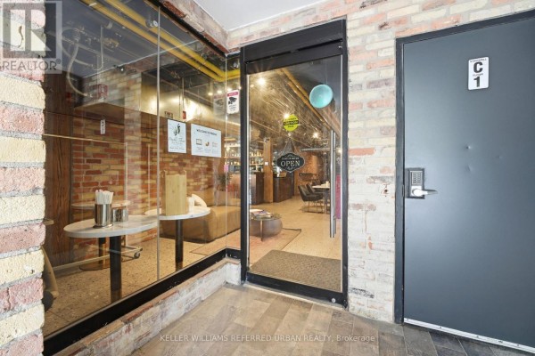 Entranceway into a commercial space with glass walls, brick interior, and modern furnishings. - #110 - 35 Mccaul Street, Toronto