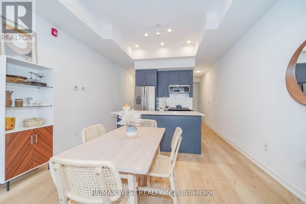 Combined dining area and kitchen with a floating shelf cabinet, island, and light wood floors. - 110 - 3686 St Clair Avenue E, Toronto
