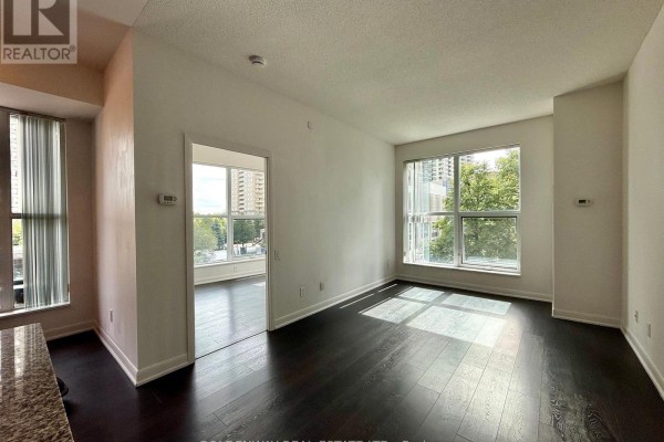Living room with dark hardwood floors, white walls, and large windows. - 110 - 5168 Yonge Street, Toronto