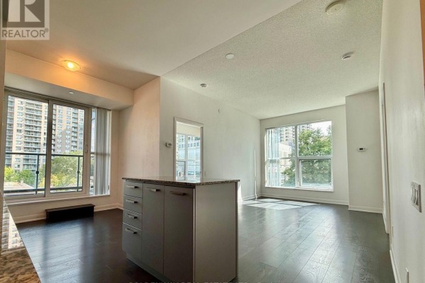 Open concept living area with kitchen island, dark hardwood floors, and city views. - 110 - 5168 Yonge Street, Toronto