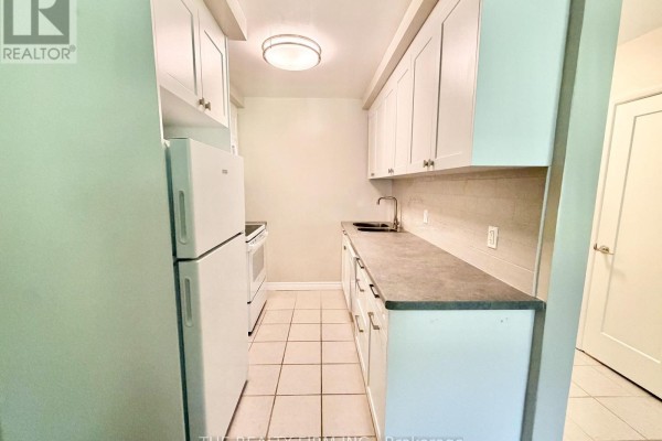 View of kitchen showing white cabinets, grey countertop, and tiled floor. - 110 - 55 Beechwood Place, London South