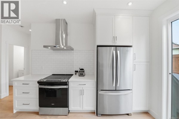 White kitchen with stainless steel appliances, including a range and refrigerator, and white cabinets. - 110 3003 Keystone Dr, Duncan