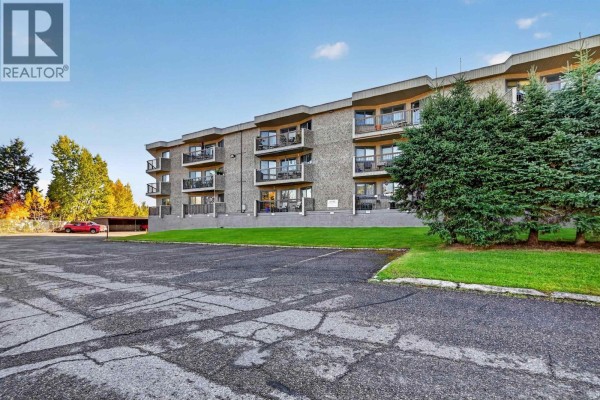Side exterior of the apartment building showing balconies and parking lot. - 110 4288 15th Avenue, Prince George