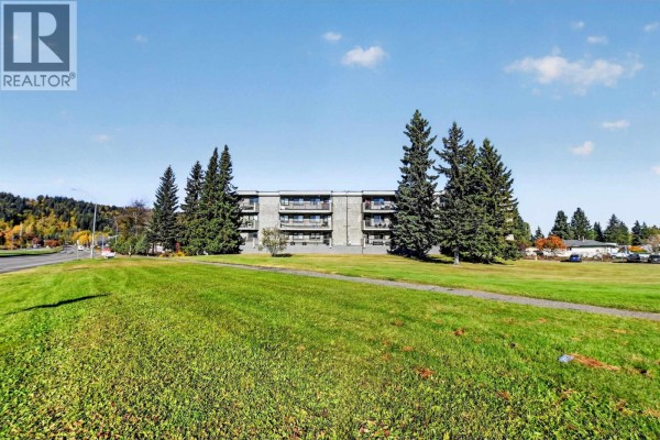 Wide view of the apartment building with a large grassy area in front. - 110 4288 15th Avenue, Prince George
