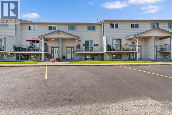 Exterior view of a townhouse complex with multiple units and parking lot in foreground. - 110 455 Killoren Crescent, Prince George
