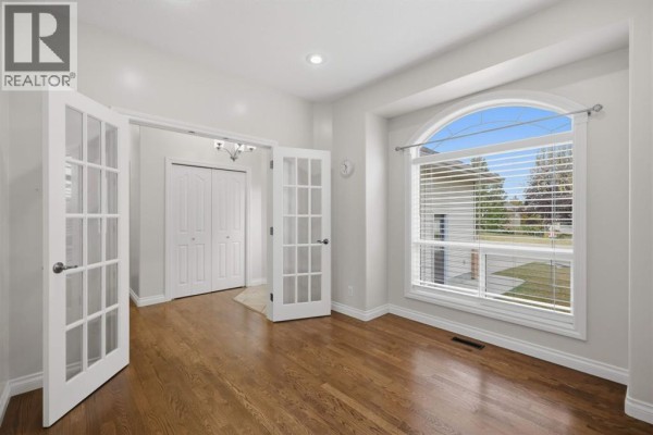 Room with French doors, wood floors, and large arched window overlooking the yard. - 110 Ainsworth Crescent, Red Deer