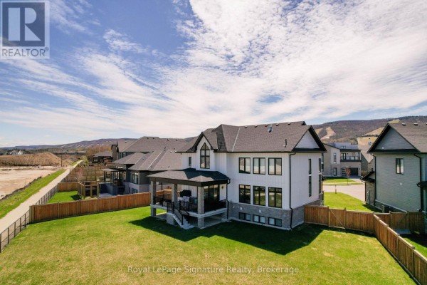 Spacious open-concept entryway with a high ceiling, dark wood stairs, and a dining area. - 110 Cattail Crescent, Blue Mountains