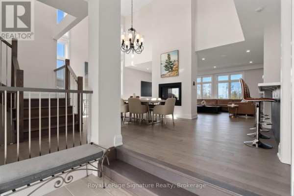 Formal dining room with a large marble table, beige chairs, and a view of the staircase. - 110 Cattail Crescent, Blue Mountains