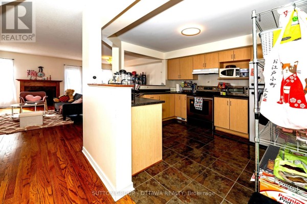 Kitchen with wooden cabinets, black counters, tile floor, and stainless steel appliances - 110 Chartley Private Ottawa