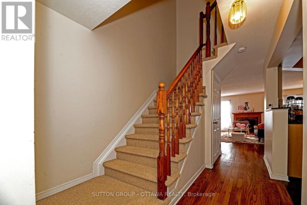 Carpeted stairs with wooden banister and hardwood floor hallway - 110 Chartley Private Ottawa