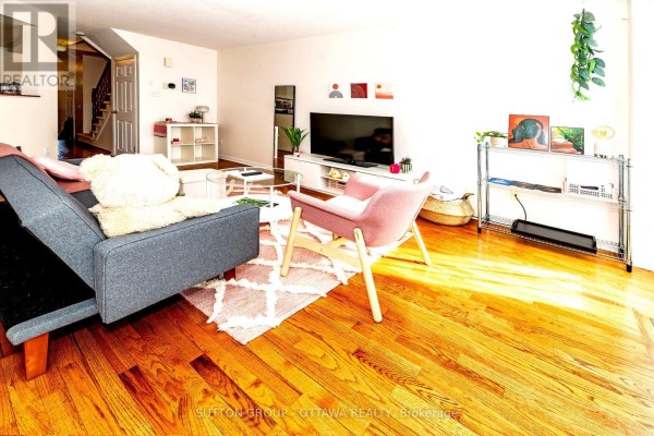 Living room with grey sofa, pink chair, glass coffee table, hardwood floors - 110 Chartley Private Ottawa