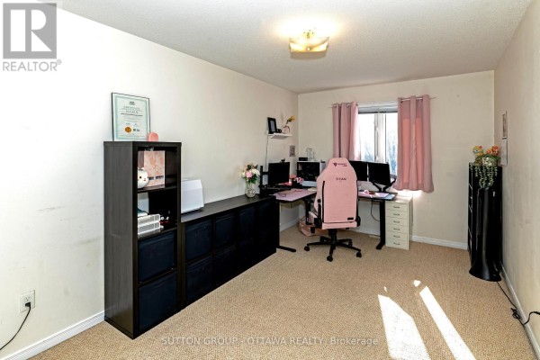 Office with pink gaming chair, dual monitors, and bookshelf - 110 Chartley Private Ottawa