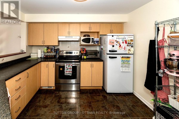 Kitchen with wood cabinets, stainless steel oven, and white refrigerator - 110 Chartley Private Ottawa