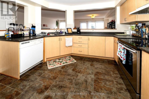Kitchen with light wood cabinets, dark counters, and pass-through window - 110 Chartley Private Ottawa