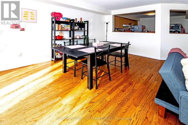 Dining area with a dark wood table and chairs next to a living room. - 110 Chartley Private, Ottawa