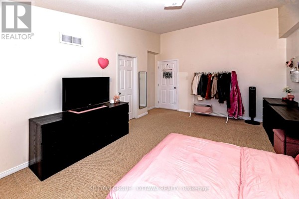 Bedroom with a king-size bed, dresser, clothing rack, and carpeted floor. - 110 Chartley Private, Ottawa