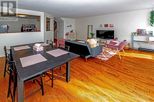 Dining area with dark table and chairs, living area with sofa and armchair - 110 Chartley Private Ottawa