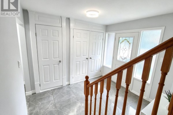 Foyer with double white doors, a front door with stained glass, and a wooden staircase railing. - 110 College Crescent, Barrie