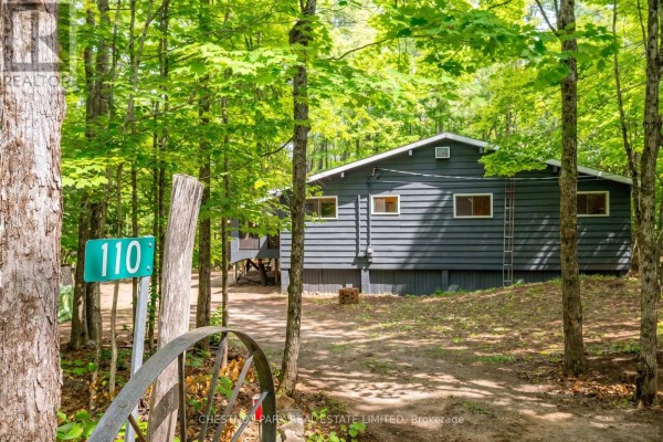 Driveway leading to the grey cottage, marked by a green sign with '110' and a metal gate. - 110 Fire Route 367, Trent Lakes