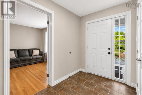 Interior entryway with tiled floor, white door with glass panels, and view into a living room. - 110 Gleneagles Drive, Hammonds Plains