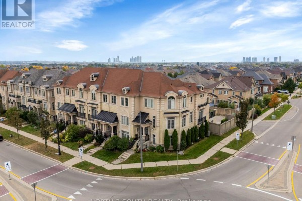 Aerial view of a beige brick townhouse complex on a street corner with trees. - 110 Grand Trunk Avenue, Vaughan