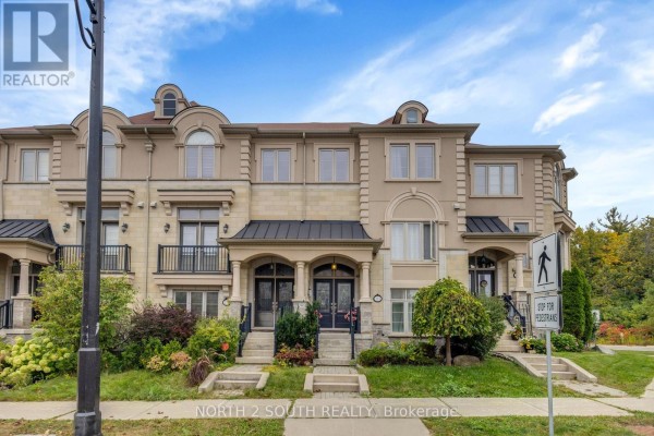 Front exterior of a beige brick townhouse with black awnings over the doors. - 110 Grand Trunk Avenue, Vaughan
