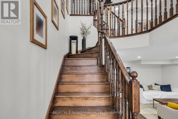 Curving wooden staircase with wooden banisters leading up from the ground floor. - 110 Grand Trunk Avenue, Vaughan