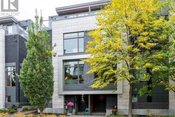 Close-up of townhouse exterior with dark wood siding and windows. - 110 Greenfield Avenue, Ottawa
