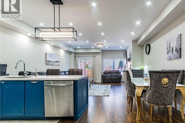 Open concept living area with a blue kitchen island, dining table, and leather sofas. - 110 Highland Road Unit# 119, Kitchener