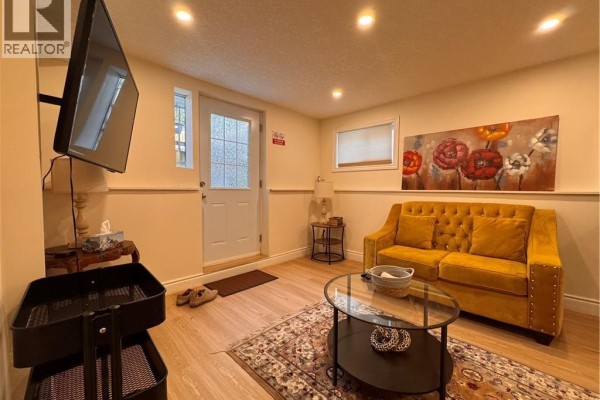 Living area with a yellow tufted sofa, coffee table, and a television. - 110 Marl Meadow Drive Unit# B, Kitchener
