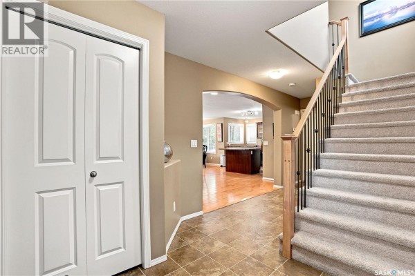 Interior hallway with beige walls, white double doors, tiled floor, and carpeted staircase. - 110 Stepney Crescent, Saskatoon