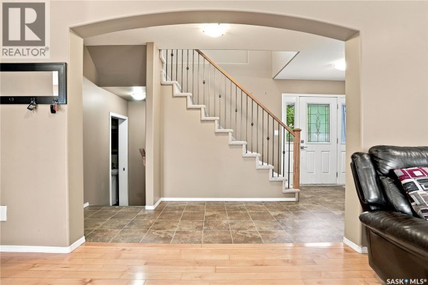 View of the foyer and staircase from the living room, showing beige walls and tiled floor. - 110 Stepney Crescent, Saskatoon