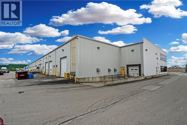 Front facade of a commercial building with glass windows, offices, and a parking lot. - 1100 South Service Road Unit# 116-216, Stoney Creek