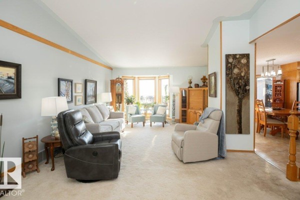 Living room with beige carpet, light blue walls, and a large bay window with natural light. - 11007 108 Av, Westlock