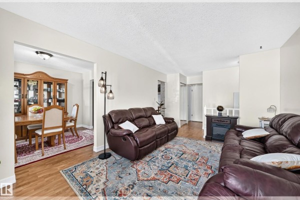 Living room and dining room with hardwood floors, leather sofas, and a china cabinet. - 11007 173a Av Nw, Edmonton
