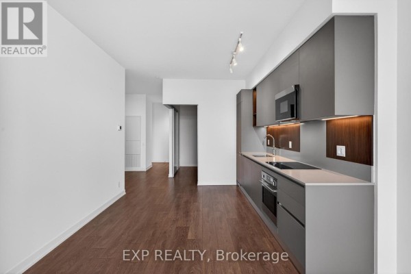 Apartment building lobby with grey tiled floor, black leather chairs, and wood accent wall. - 1101 - 39 Mary Street, Barrie