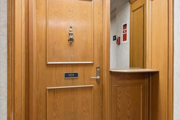 Apartment 1101 wood front door with a knocker, peephole, and a small pass-through shelf. - 1101 - 4 Willow Street, Waterloo