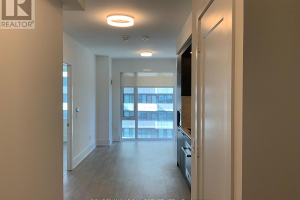 Hallway looking into an open-concept living area with large windows and light wood floors. - 1101 - 470 Front Street W, Toronto