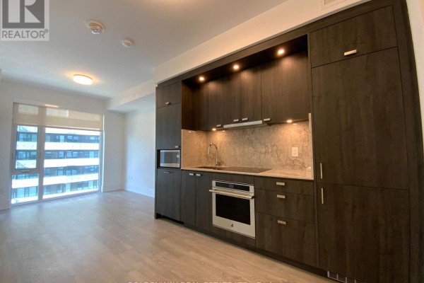 Modern kitchen with dark wood cabinets, stainless steel appliances, and a marble backsplash. - 1101 - 470 Front Street W, Toronto