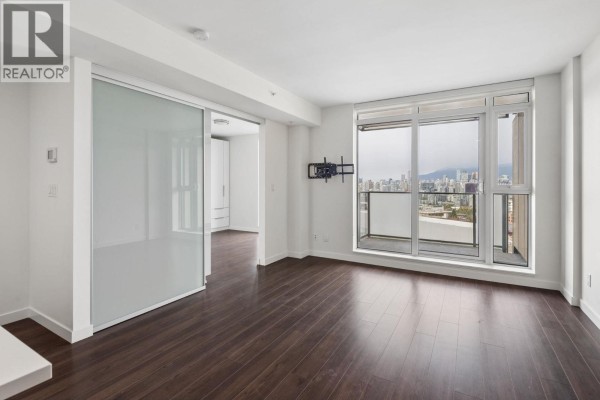 Empty living room with dark wood floors, large windows, and city view. - 1101 285 E 10th Avenue, Vancouver