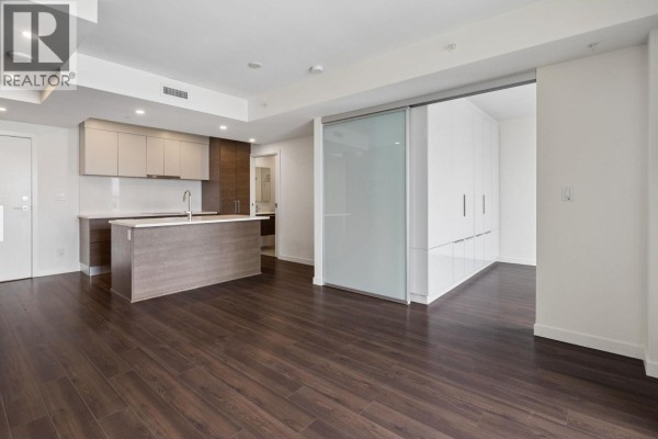Open concept living area with island kitchen, dark wood floors, and sliding doors. - 1101 285 E 10th Avenue, Vancouver