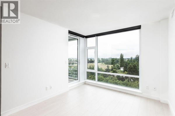 Empty room with white walls, light wood floors, and a balcony door. - 1101 8800 Hazelbridge Way, Richmond