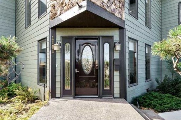 Close-up of the dark brown front door with oval glass, flanked by windows and sidelights. - 1101 Centre Street, Bow Island