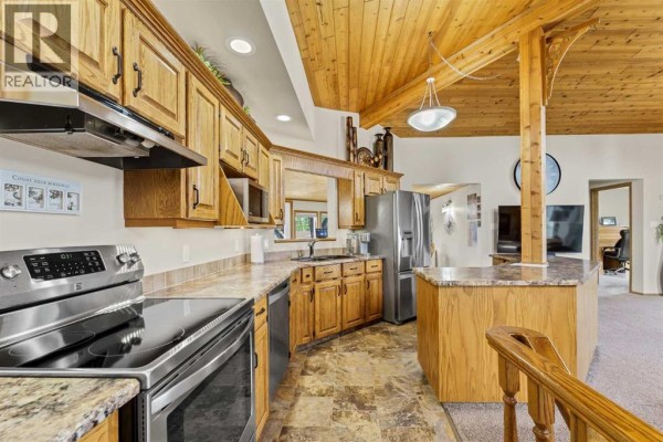 Kitchen with light oak cabinets, stainless steel appliances, granite countertops, and island. - 1101 Centre Street, Bow Island