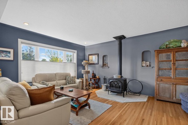 Living room with a wood-burning stove, blue walls, and two white sofas. - 11010 110 Av Nw, Edmonton