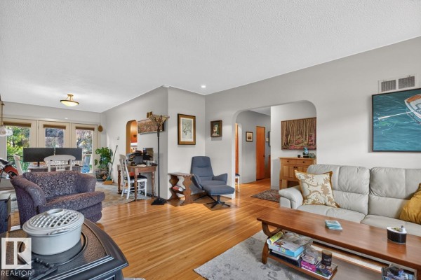 Living room and dining area with wood floors, white walls, and furniture. - 11010 110 Av Nw, Edmonton