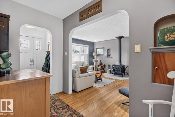 View through an arched doorway into a living room with a wood stove and sofas. - 11010 110 Av Nw, Edmonton