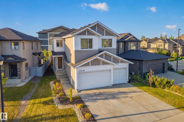 Daytime aerial view of a two-story house with a gray and white exterior and a triple-car garage. - 11010 174a Av Nw, Edmonton