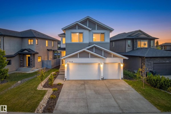 Twilight exterior view of a modern two-story house with a gray and white siding and a garage. - 11010 174a Av Nw, Edmonton